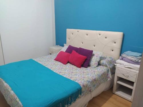 um quarto com uma cama com almofadas roxas e vermelhas em Casa con pileta en Rosario em Rosário