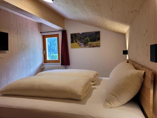Bett in einem Zimmer mit Fenster in der Unterkunft Alpenglück Montafon in Sankt Gallenkirch
