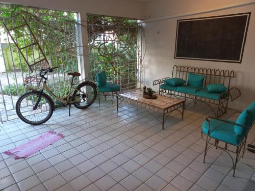 una bicicleta estacionada en una habitación con sillas y una pizarra en Pousada jardim de cabo branco en João Pessoa