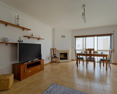 a living room with a table and a tv and a dining room at Alojamento Santo António II in Nazaré