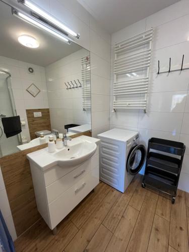 a bathroom with a sink and a washing machine at Apartament H204 z widokiem na basen in Kołobrzeg