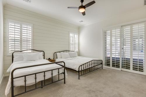 Goodyear Vacation Rental with Private Hot Tub في غوديير: سريرين في غرفة نوم بجدران بيضاء ونوافذ