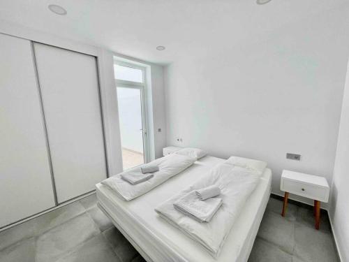 a white bedroom with two beds and a large mirror at Weybeach 7 - New, modern, stylish, fully equipped in La Santa