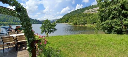 a view of a river with people sitting on a bench at Aurora on the lake in Fužine