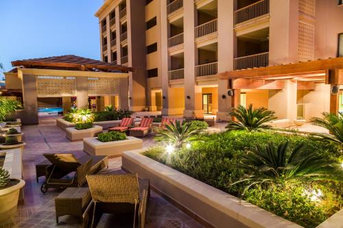 a hotel patio with tables and chairs and plants at Sedra Arjaan by Rotana in Doha