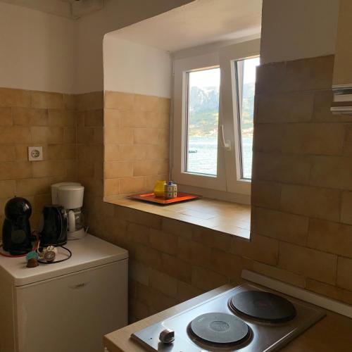 a small kitchen with a stove and a window at Marija Seršić “Narca” in Baška