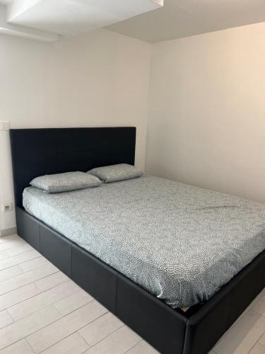 Ce lit se trouve dans un dortoir doté d'un cadre de lit noir. dans l'établissement Appartement au bor de mer, à Marseille