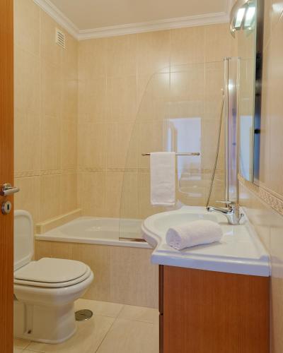a bathroom with a sink and a toilet and a tub at Alojamento Santo António II in Nazaré