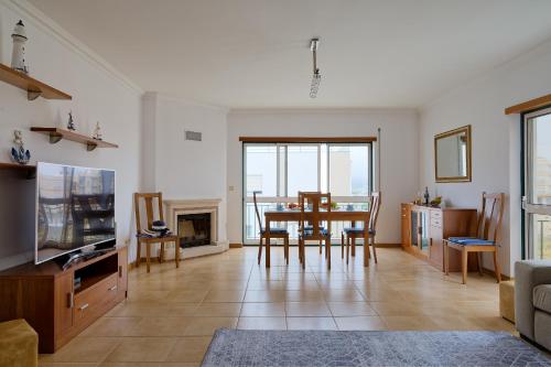 a living room with a table and chairs and a tv at Alojamento Santo António II in Nazaré