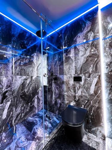 a bathroom with a black toilet and a blue light at Boutique Studio Apartment in Ventspils