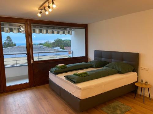Cama en habitación con ventana grande en Apartment Bergpanorama mit wunderschönem Alpenpanorama und Indoor-Pool, en Oberteuringen