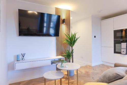 a living room with a couch and a tv on a wall at Luxurious City Centre Apartment in Perth