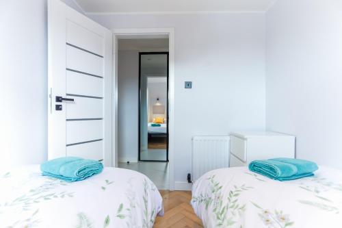 two beds in a bedroom with white walls and blue pillows at Luxurious City Centre Apartment in Perth