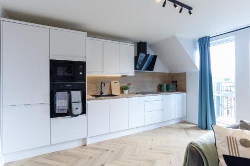a kitchen with white cabinets and a large window at Luxurious City Centre Apartment in Perth