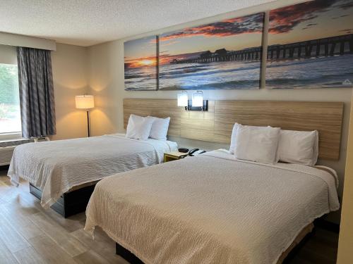 a hotel room with two beds and a painting on the wall at Days Inn by Wyndham Blythewood North Columbia in Blythewood