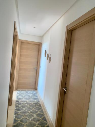 - un couloir avec deux portes en bois et un tapis dans l'établissement Prestigia plage des nations , OCEAN VIEW, à Sidi Bouqnadel