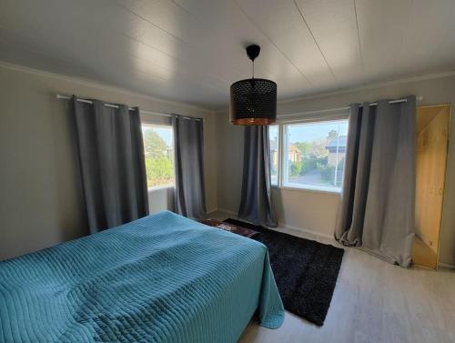 a bedroom with a blue bed and windows at Omakotitalo rauhallisella alueella in Rauma