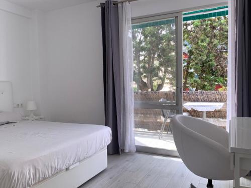 a bedroom with a bed and a chair and a window at Entre el verde y el azul in Fuengirola
