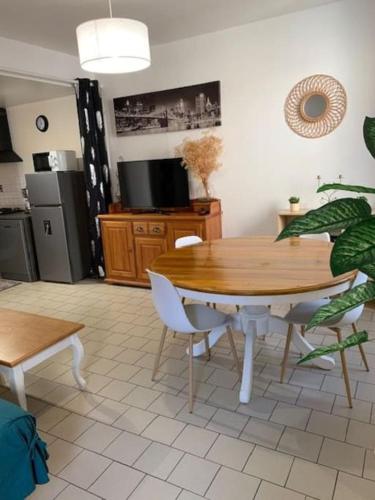 a dining room with a table and chairs and a kitchen at La Vallée Claire in Le Blanc