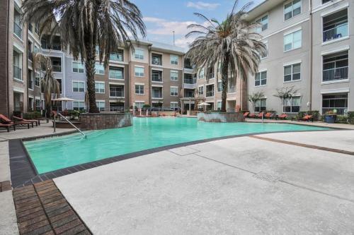 a large swimming pool with palm trees and a building at Lux Mid-Rise Walking Distance to NRG Stadium in Houston