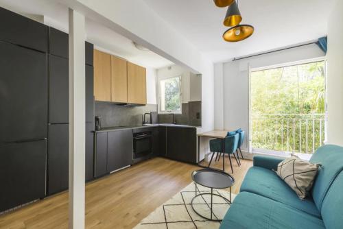 sala de estar con sofá azul y cocina en Appartement 2 pièces 4 couchages tout confort, en Neuilly-sur-Seine