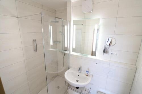 ein weißes Bad mit einer Dusche und einem Waschbecken in der Unterkunft Frische Brise 12.03 in Cuxhaven