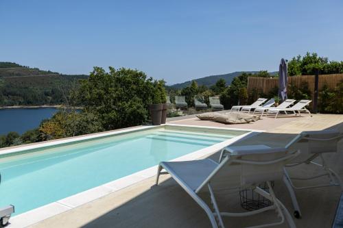 einen Pool mit Stühlen und Blick auf das Wasser in der Unterkunft Villa Gerês Emblematico - Piscina & Jacuzzi in Venda Nova
