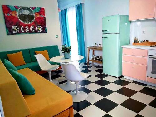 a living room with a couch and a table and a kitchen at Nostalgia Retro Suites in Naxos Chora