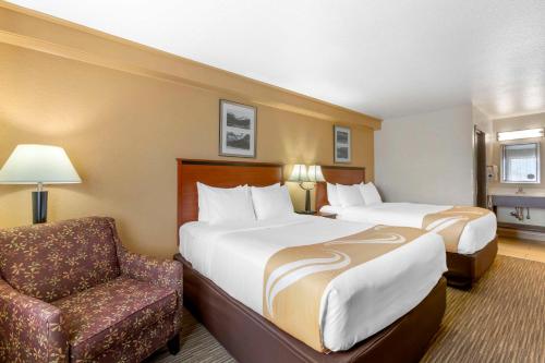 una habitación de hotel con 2 camas y una silla en Quality Inn Hamilton Bitterroot Valley, en Hamilton