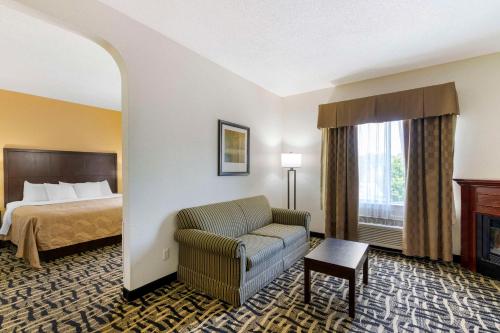a hotel room with a bed and a couch and a chair at Quality Suites La Grange in La Grange