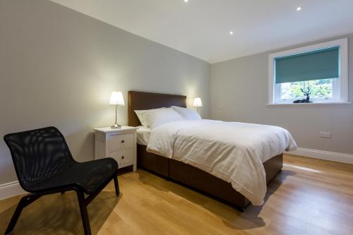 a bedroom with a bed and a chair and a window at The Lion Gate Mews in Kingston upon Thames