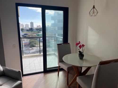 a dining room with a table and chairs and a large window at Flat Premium -Acesso a pé ao shopping Center vale - Edifício Summit (Ar condicionado) in São José dos Campos
