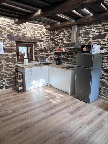 a kitchen with white appliances and a stone wall at El Rincón del Val in Priaranza del Bierzo