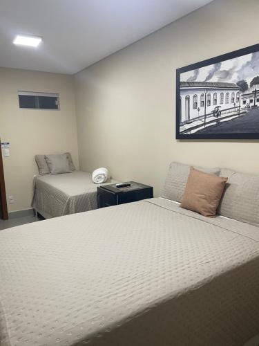 a bedroom with two beds and a painting on the wall at Hotel Santa Maria in Pirenópolis