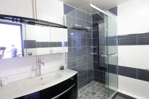 a bathroom with a sink and a glass shower at Bel Appartement proche Paris 16eme in Boulogne-Billancourt