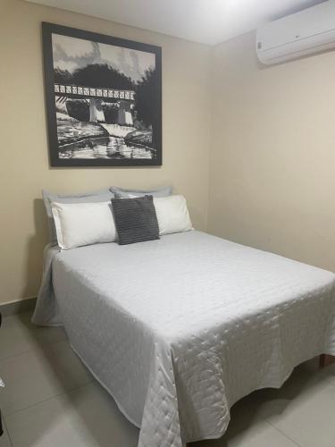 a bedroom with a bed with white sheets and a picture at Hotel Santa Maria in Pirenópolis