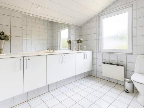 Bøtø ByにあるHoliday home Væggerløse XXXIVの白いタイル張りのバスルーム(トイレ、窓付)
