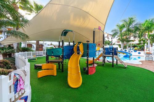 a playground with a slide on a green lawn at Dúplex en las Americas 3014 in Arona