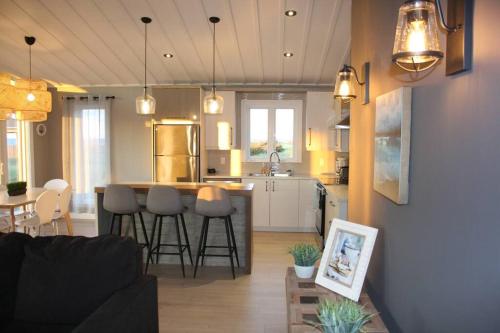 a living room and a kitchen with a counter and chairs at Luxueux chalet sur la plage - Baie des Chaleurs in Caraquet
