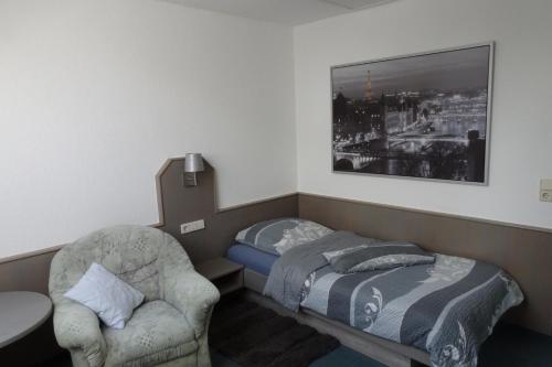 Pension Egerer في Bad Köstritz: غرفة نوم صغيرة بها سرير وكرسي
