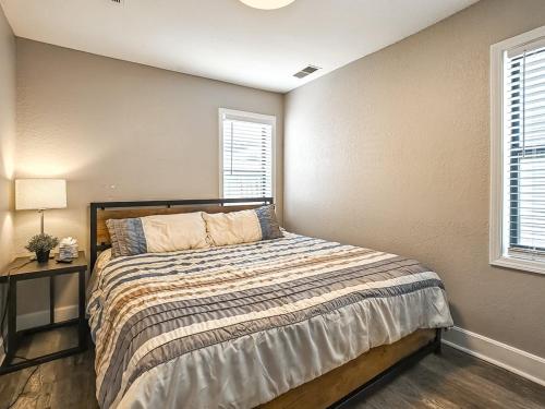 a bedroom with a bed and a table and two windows at Heart of Westport 1BR in Kansas City