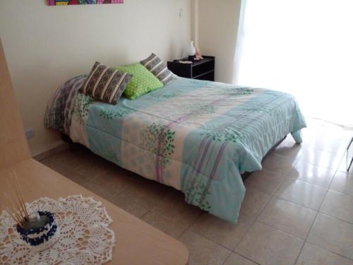 Un dormitorio con una cama con almohadas verdes. en Buenos Aires Tango Apartment near Golf en San Antonio de Padua