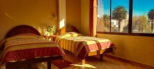 two beds in a room with a window at Hotel El Super 8 in Cochabamba