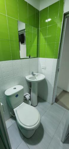 baño verde y blanco con aseo y lavabo en Hotel Noz INN, en Villavicencio