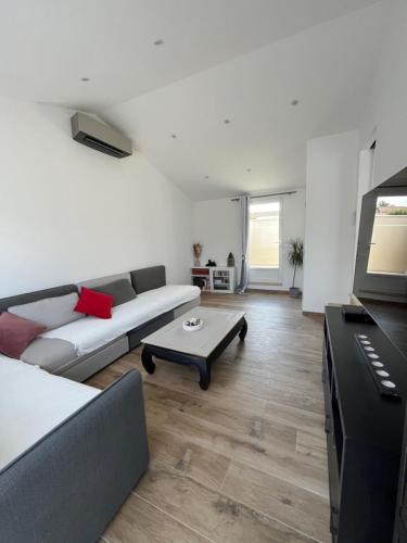 ein Wohnzimmer mit einem Sofa und einem Tisch in der Unterkunft Villa provençale avec piscine in Saint-Andiol