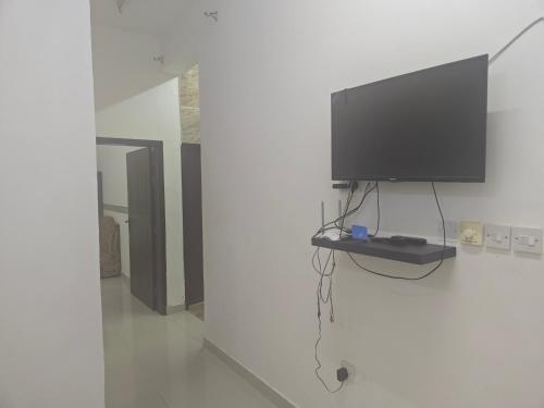 TV de pantalla plana colgada en una pared blanca en شقق وادي ذنه, en Salalah