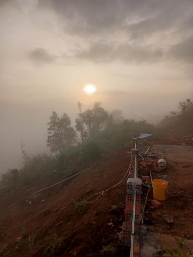 a misty sunrise on a hill with the sun in the background at THIÊN HƯƠNG Homestay Măng Đen in Kon Von Kla