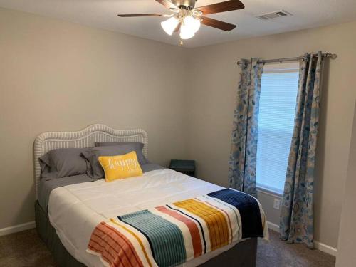 Schlafzimmer mit einem Bett, einem Deckenventilator und einem Fenster in der Unterkunft Comfy, Stylish Townhome Near I-20! in Augusta