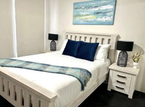 - une chambre avec un lit blanc et des oreillers bleus dans l'établissement Ebbtide 3, à Forster