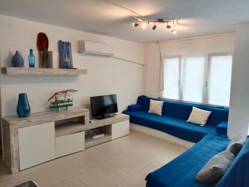 a living room with a blue couch and a tv at Apartamento completo en Cadaqués in Cadaqués